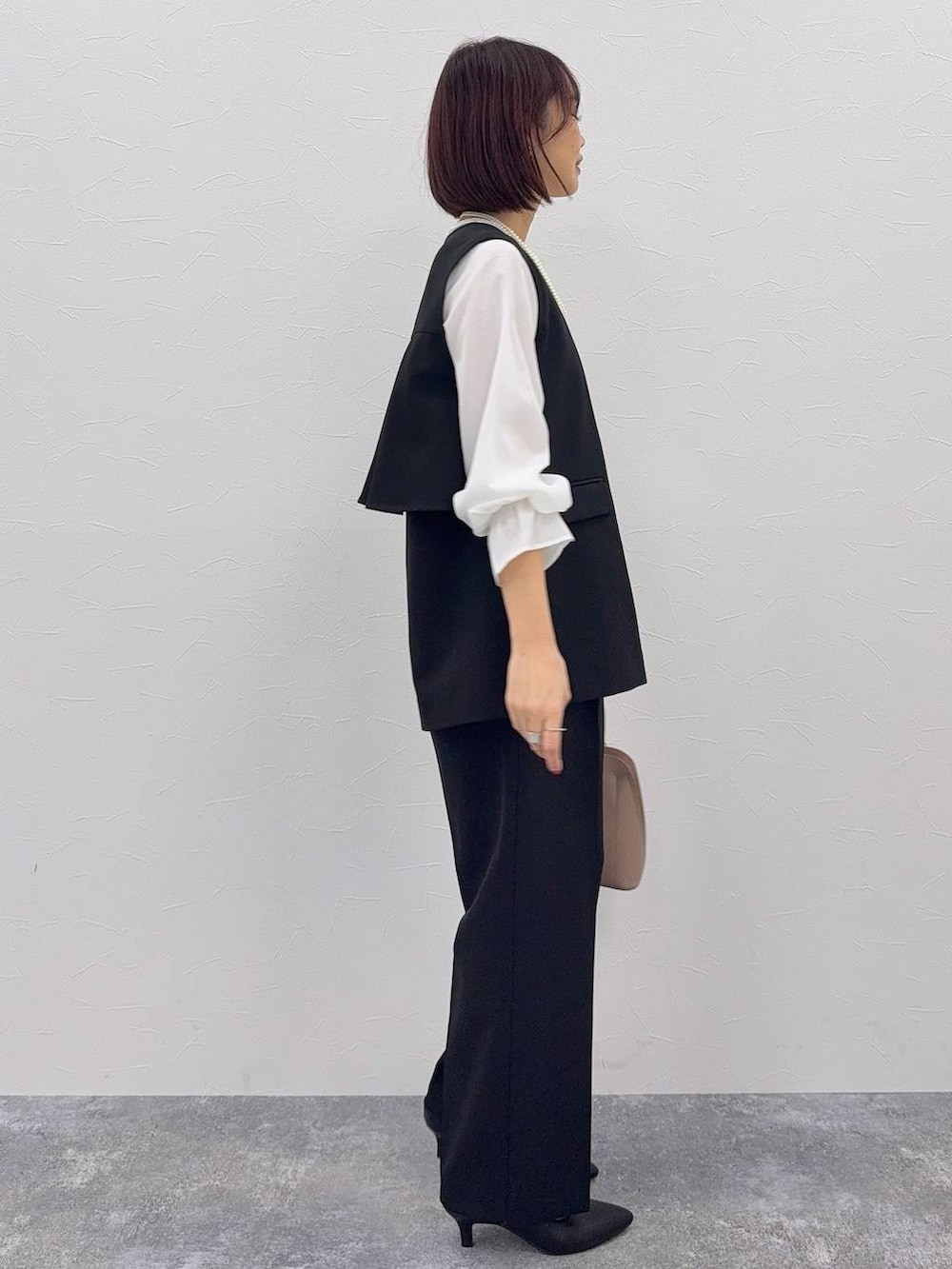 ベージュ系のショルダーバッグ、ブラック系のパンプス、その他のネックレスを着用したレディースの秋コーディネートの2枚目の写真