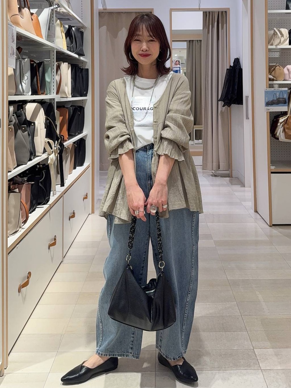 ブラック系のパンプス、ブルー系のデニムパンツ、ホワイト系のスウェットを着用したレディースの春コーディネートの3枚目の写真