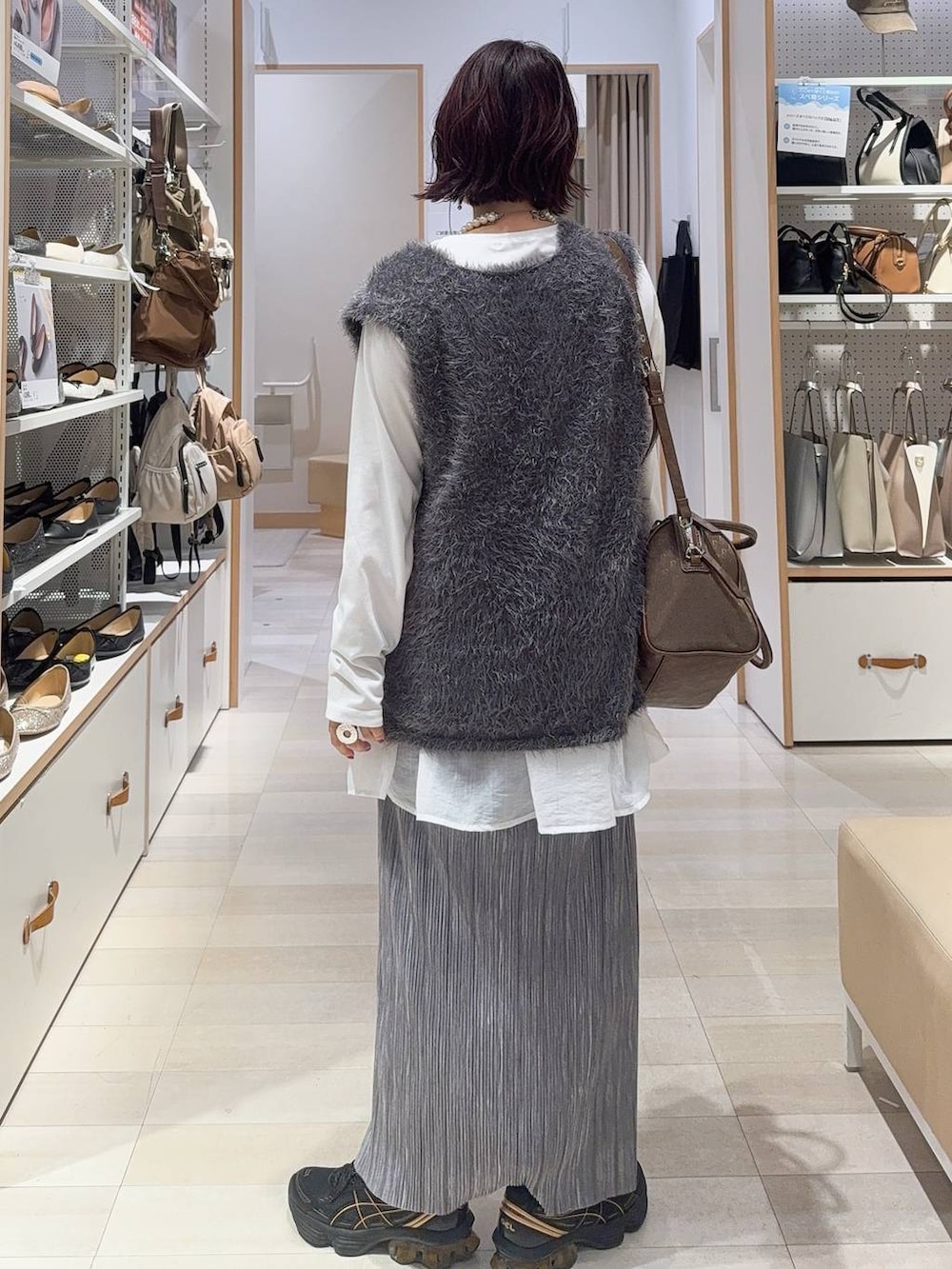 グリーン系のボストンバッグ、ホワイト系のブルゾン、グレー系のスカートを着用したレディースの秋コーディネートの8枚目の写真