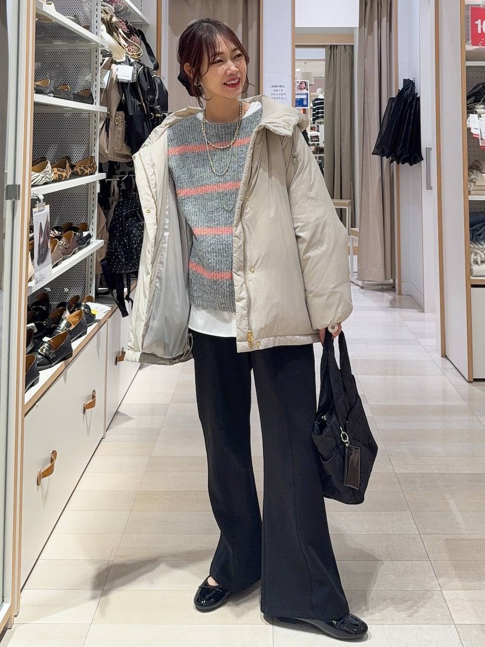 ゴールド系のバレエシューズ、ブラック系のトートバッグ、ベージュ系のダウンジャケット/コートを着用したレディースの冬コーディネートの2枚目の写真