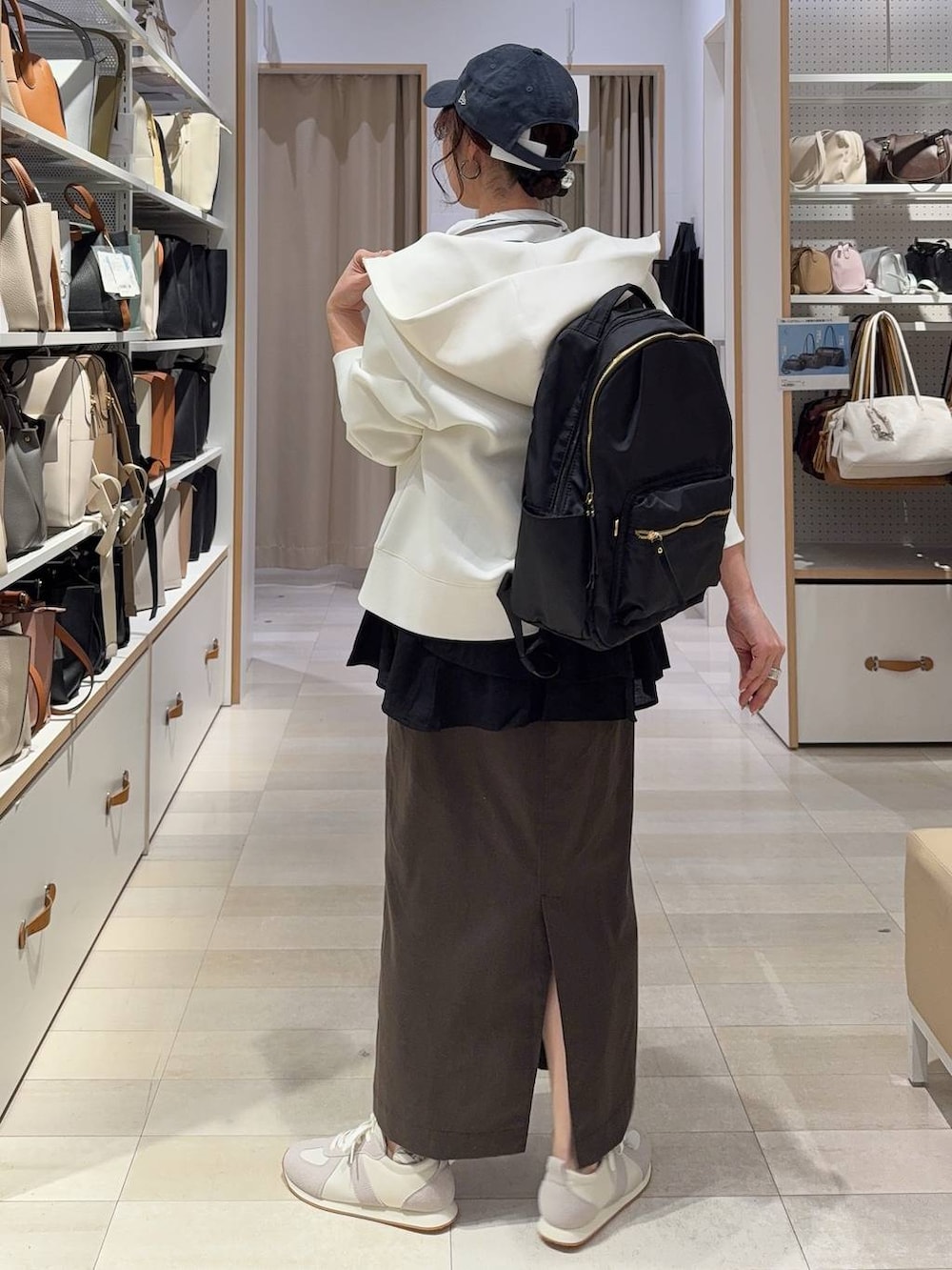 グレー系のスニーカー、ブラック系のバックパック/リュック、ホワイト系のパーカーを着用したレディースの春コーディネートの5枚目の写真