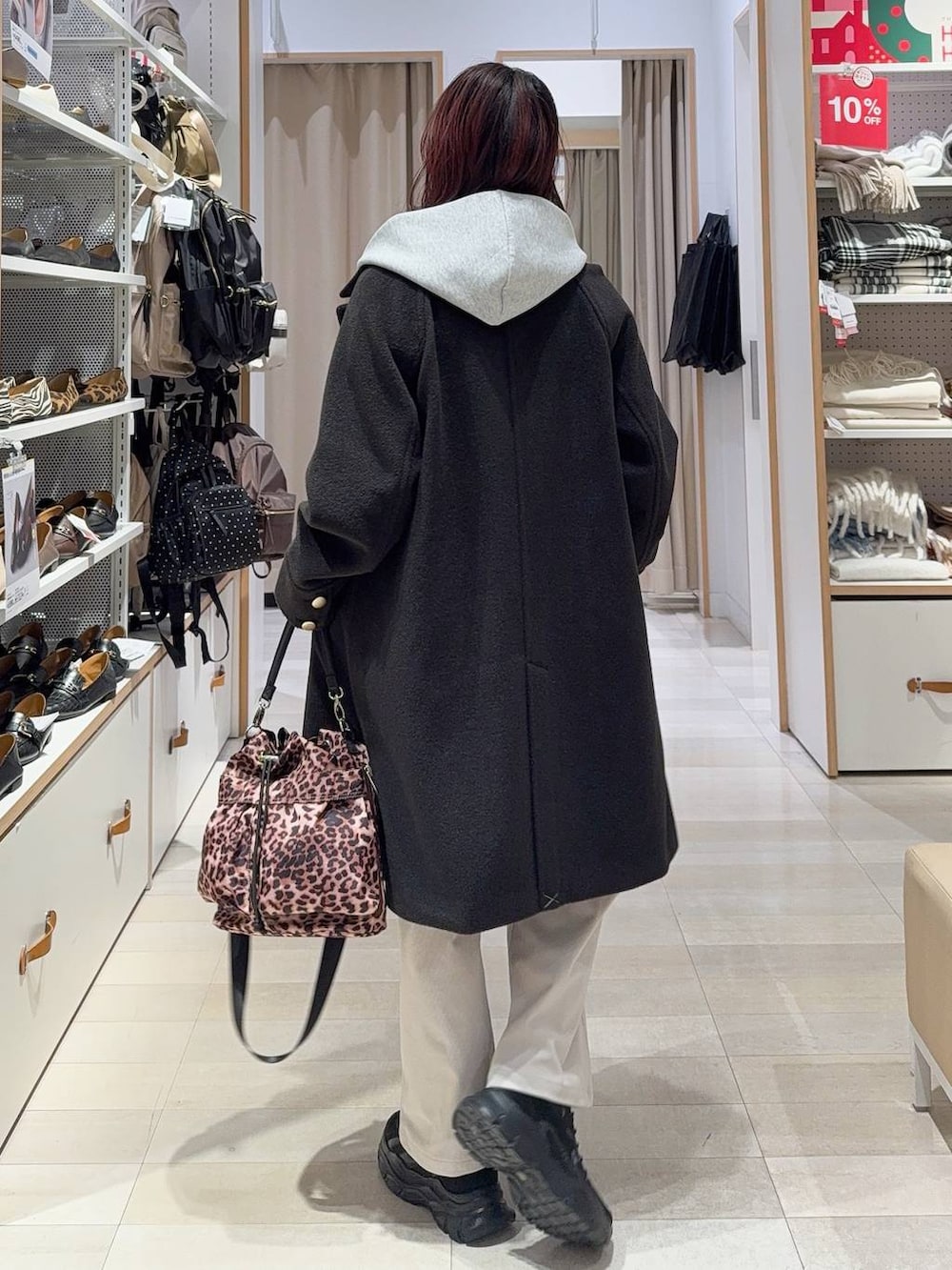 ブラック系のチェスターコート、グレー系のその他パンツ、ブラック系のスニーカーを着用したレディースの冬コーディネートの4枚目の写真