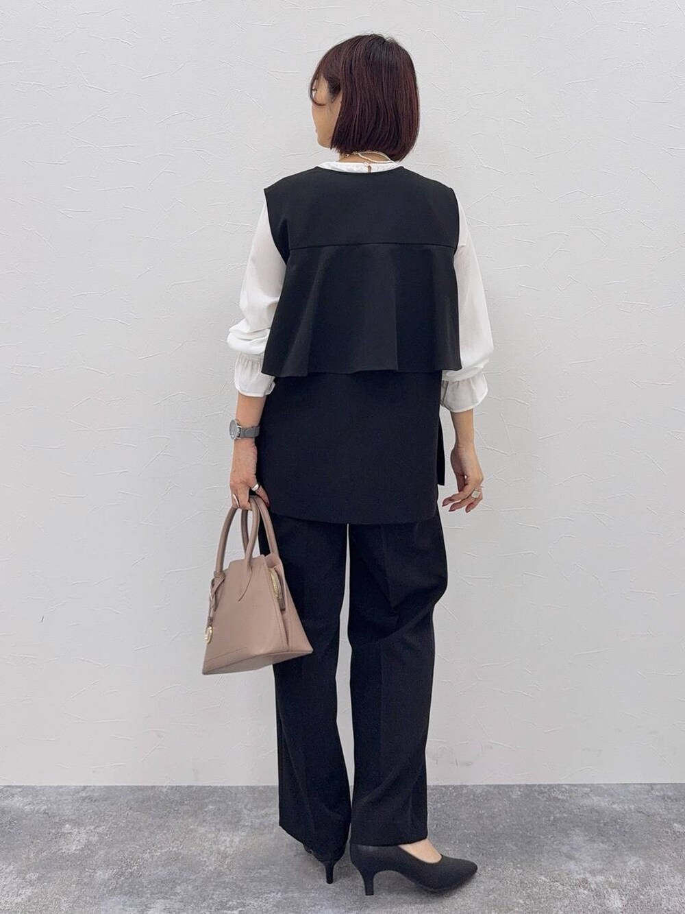 ベージュ系のショルダーバッグ、ブラック系のパンプス、その他のネックレスを着用したレディースの秋コーディネートの3枚目の写真