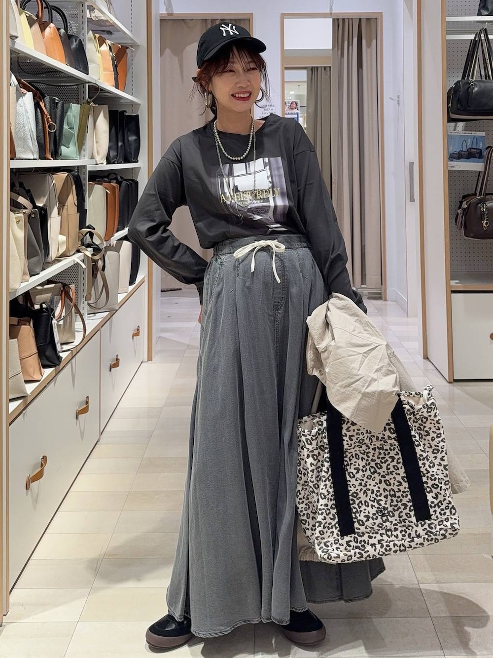 ブラック系のスニーカー、ベージュ系のパーカー、ブラウン系のトートバッグを着用したレディースの春コーディネートの2枚目の写真