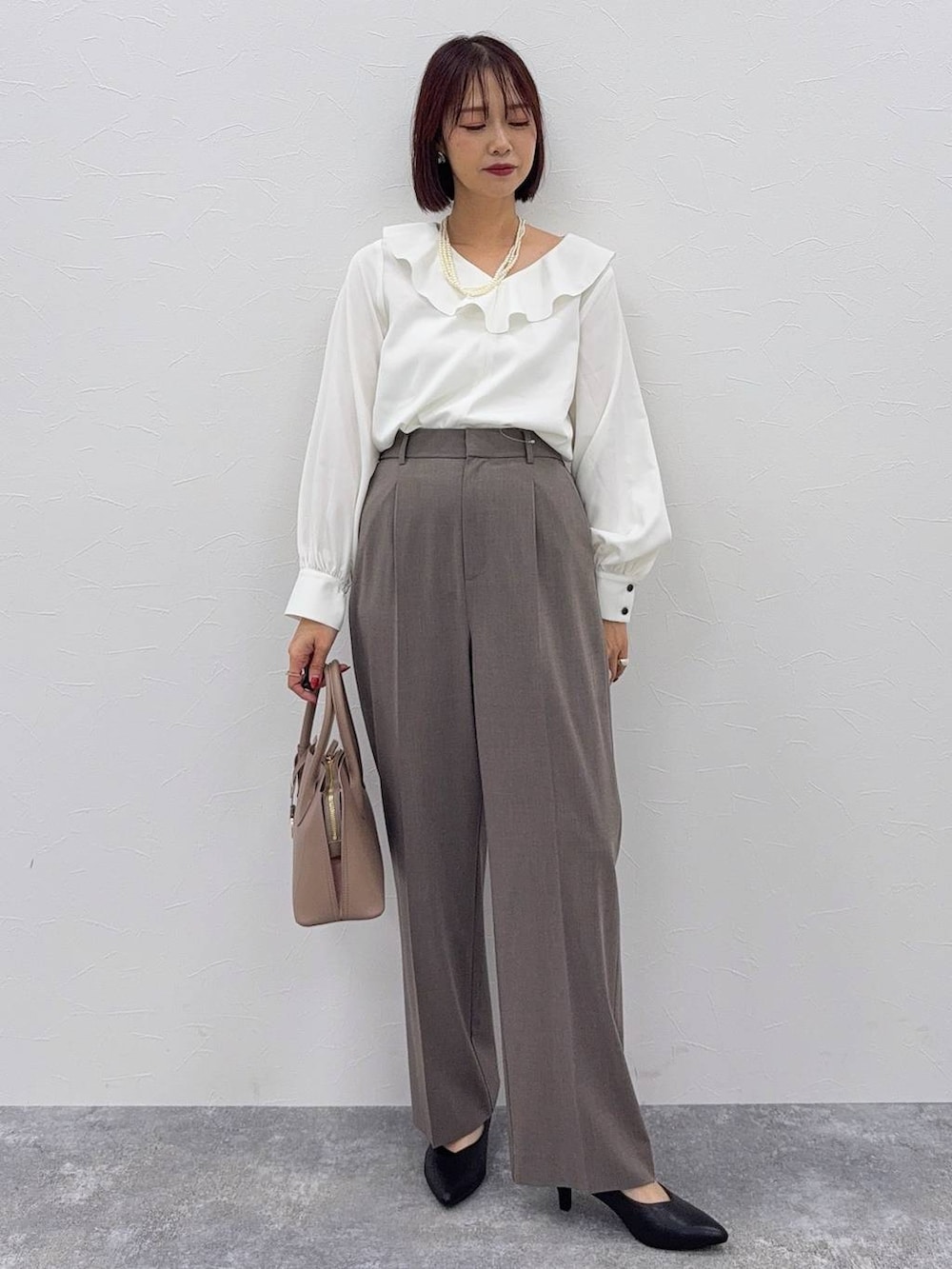 ベージュ系のショルダーバッグ、ブラック系のパンプス、ブラウン系のスラックスを着用したレディースの秋コーディネートの2枚目の写真