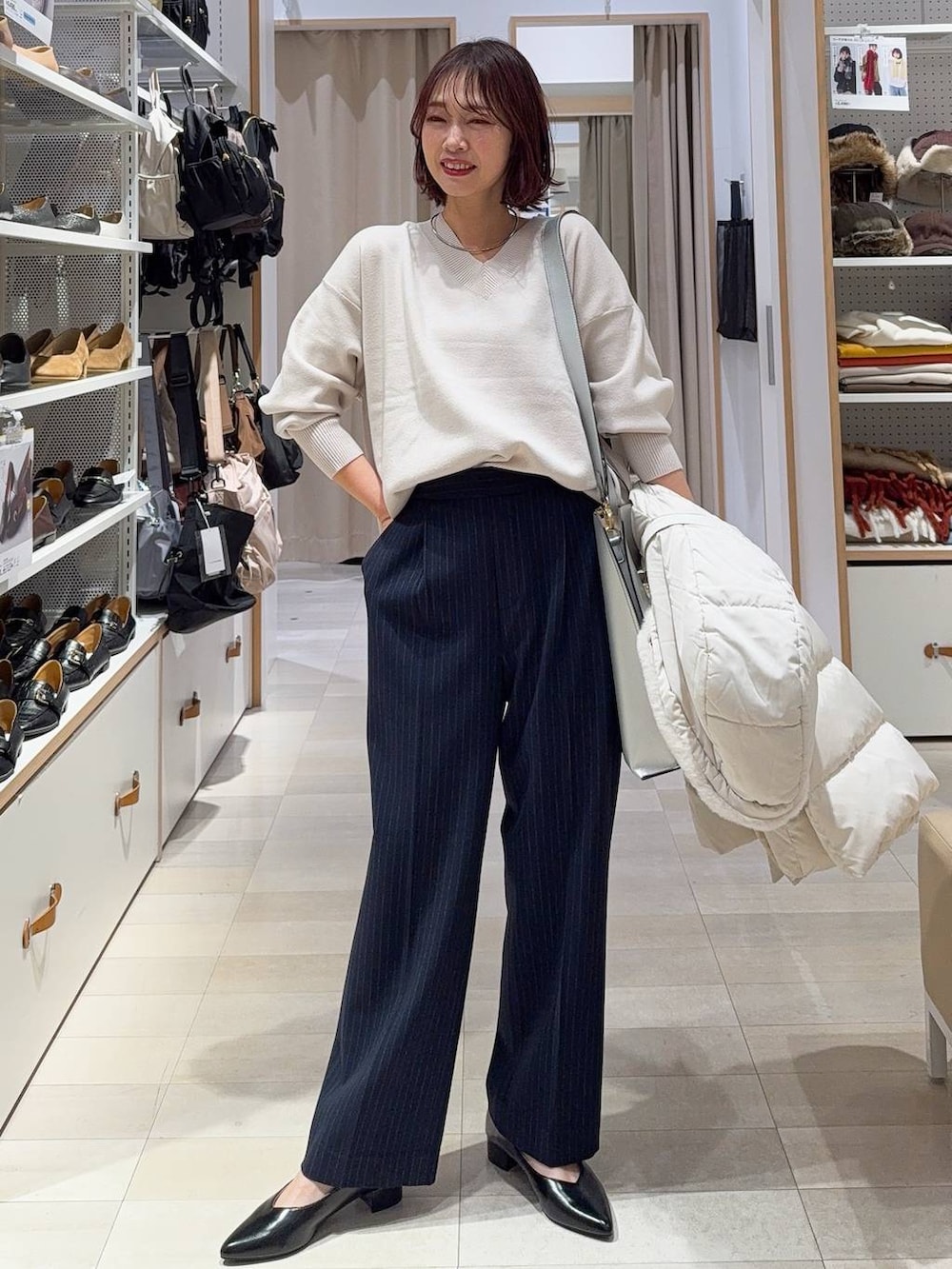 シルバー系のトートバッグ、ベージュ系のダウンジャケット/コート、ホワイト系のニット/セーターを着用したレディースの冬コーディネートの3枚目の写真