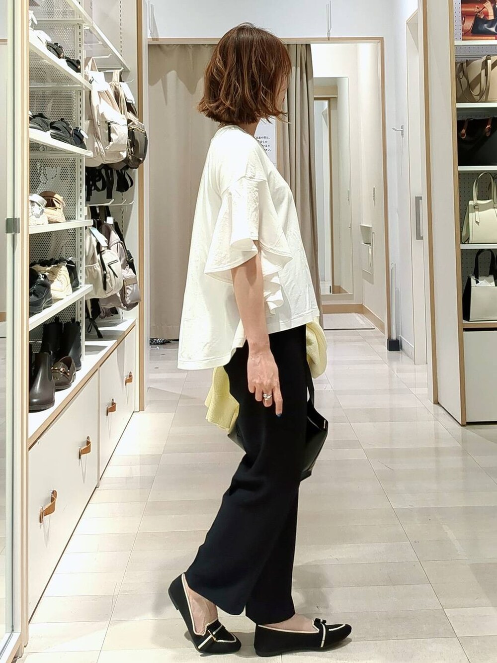 ブラック系のショルダーバッグ、イエロー系のカーディガン/ボレロ、その他のパンプスを着用したレディースの春コーディネートの6枚目の写真