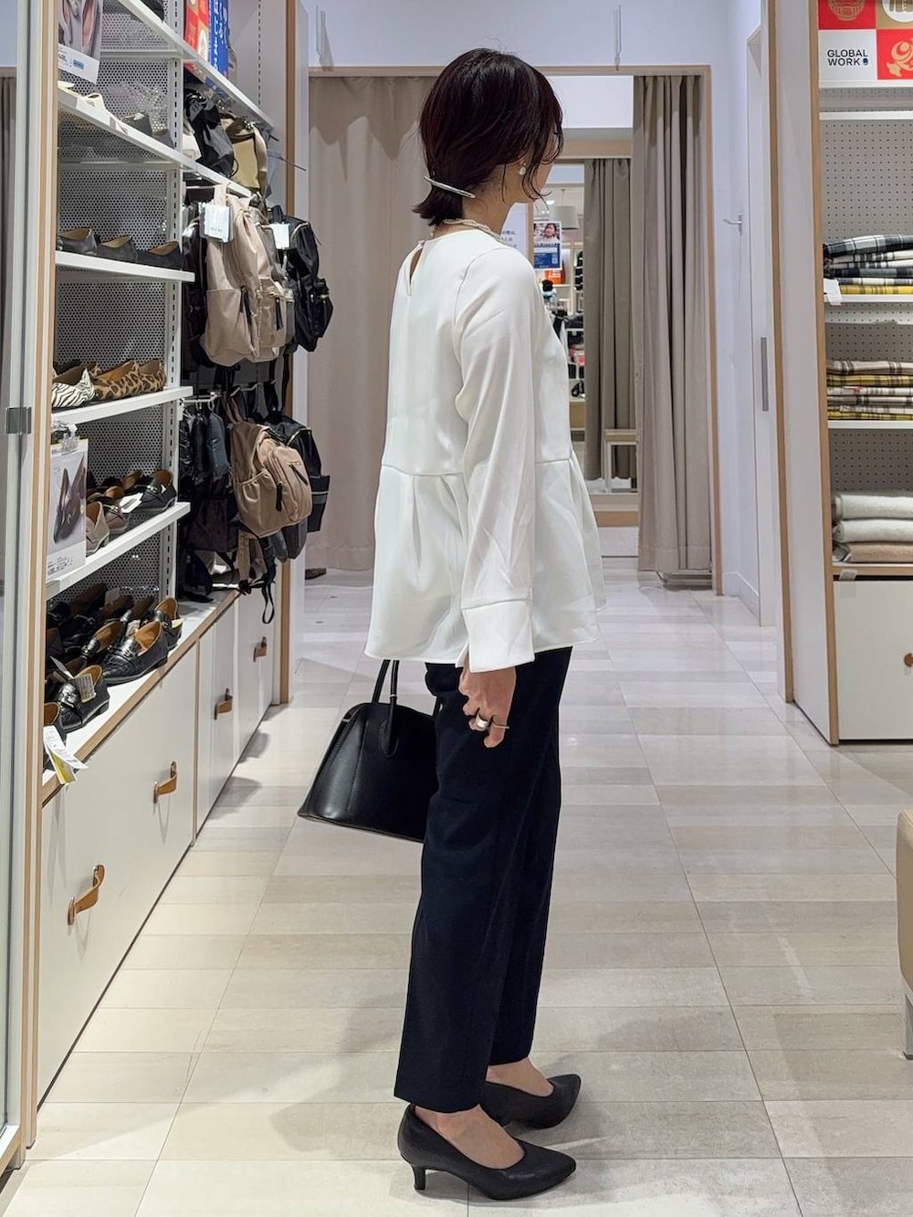 ブラック系のショルダーバッグ、ブラック系のパンプス、ブルー系のセットアップを着用したレディースの冬コーディネートの7枚目の写真