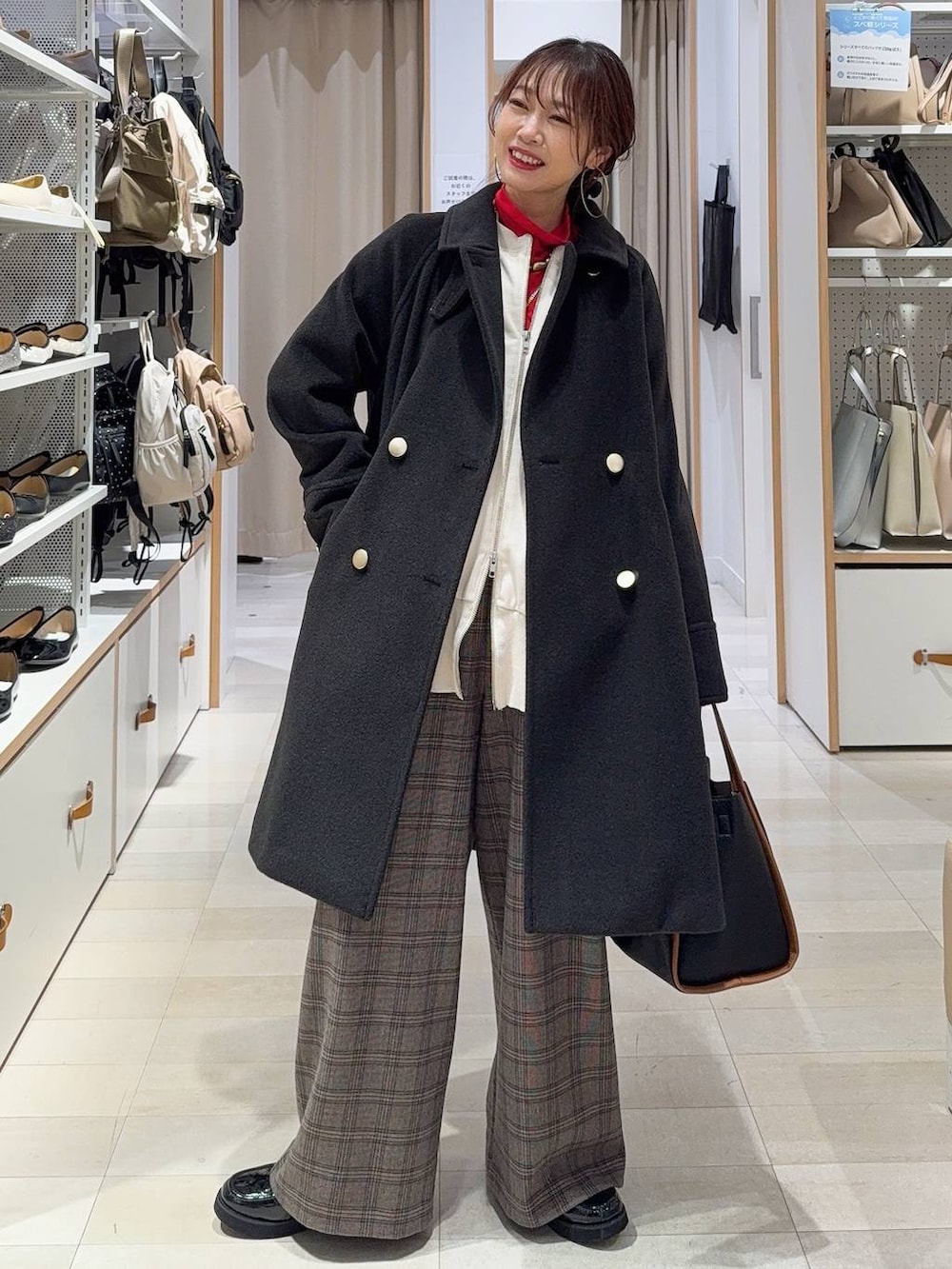 ブラック系のチェスターコート、ブラック系のショルダーバッグ、ホワイト系のTシャツ/カットソーを着用したレディースの秋コーディネートの4枚目の写真