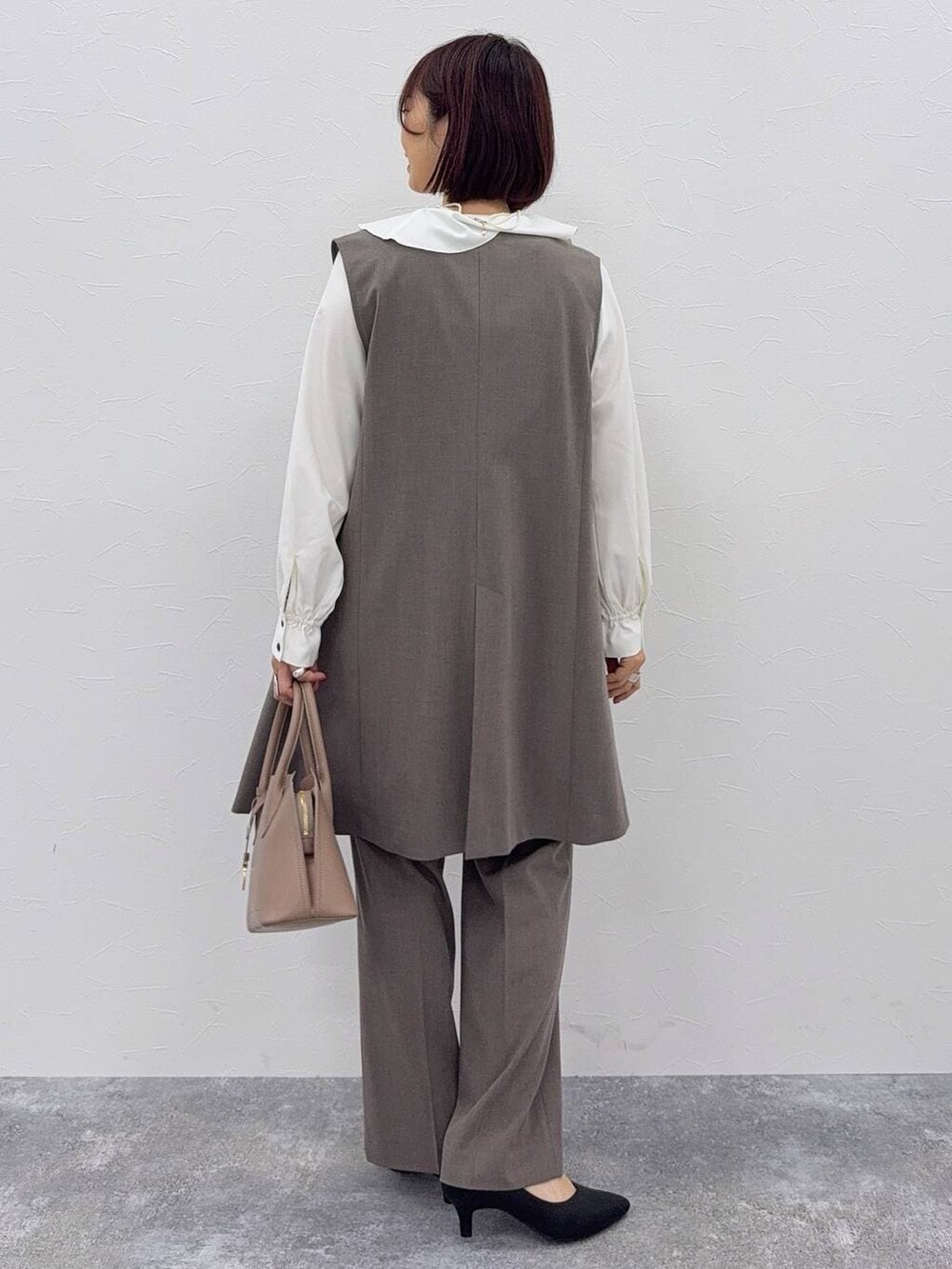 ベージュ系のショルダーバッグ、ブラック系のパンプス、ブラウン系のスラックスを着用したレディースの秋コーディネートの4枚目の写真