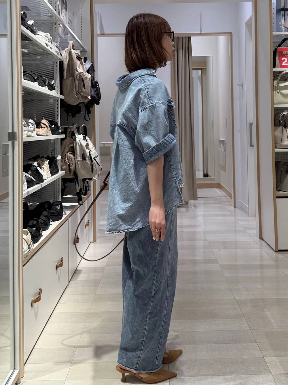 ベージュ系のパンプス、グリーン系のボストンバッグ、ブルー系のデニムパンツを着用したレディースの春コーディネートの3枚目の写真