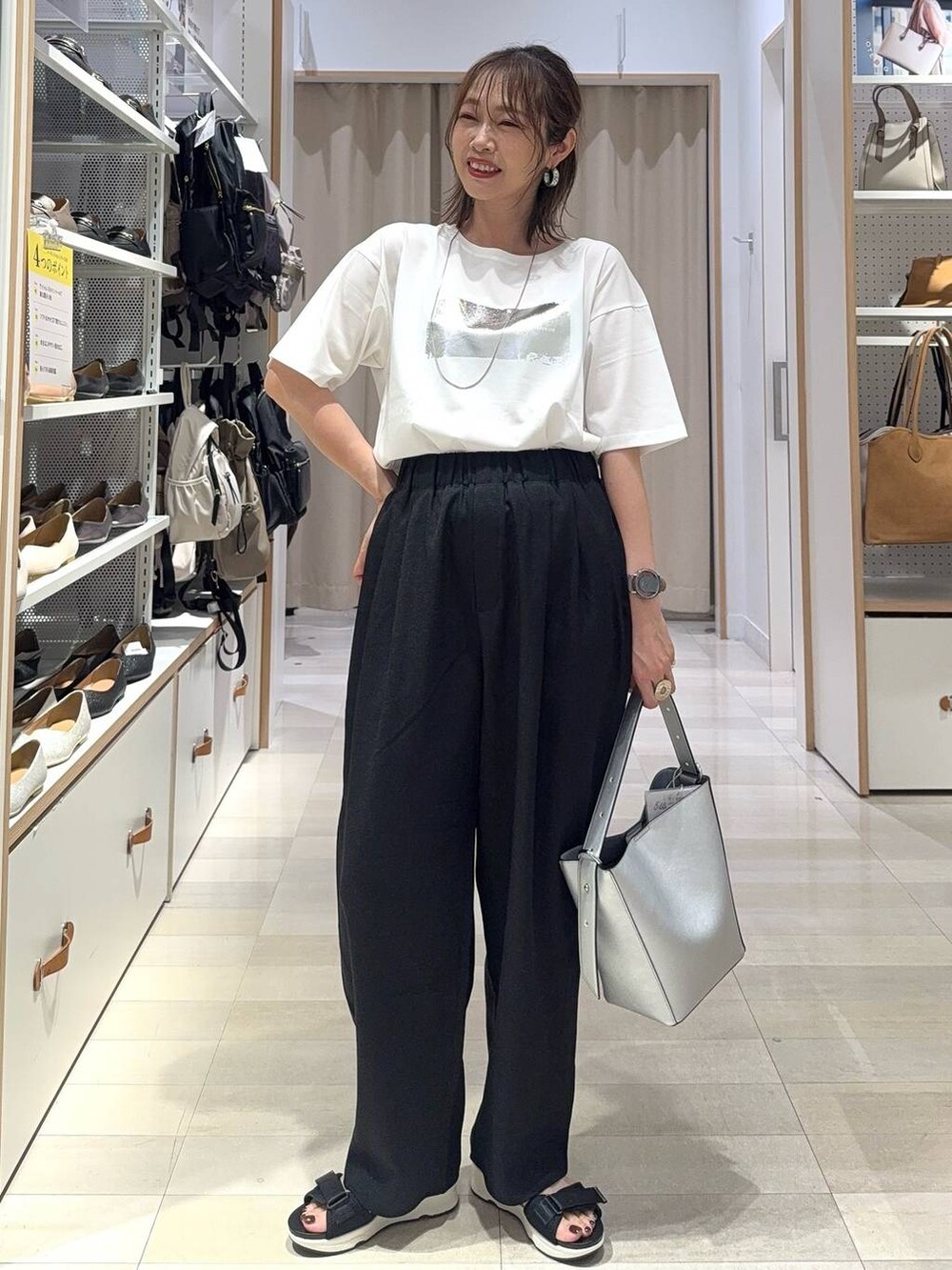 シルバー系のショルダーバッグ、ブラック系のTシャツ/カットソー、シルバー系のサンダルを着用したレディースの夏コーディネートの3枚目の写真