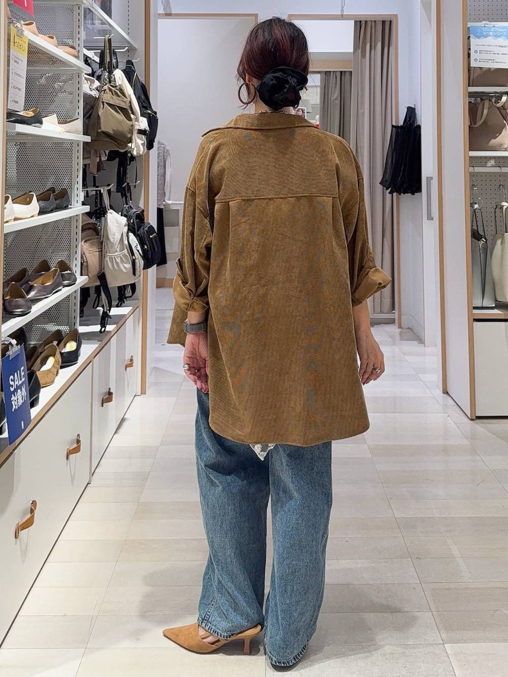 グリーン系のボストンバッグ、ベージュ系のキャミソール、ブルー系のデニムパンツを着用したレディースの秋コーディネートの6枚目の写真