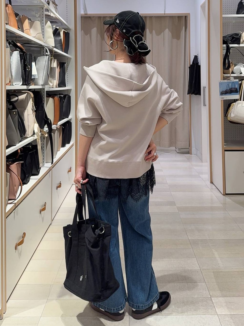 ブラック系のスニーカー、ブルー系のデニムパンツ、ベージュ系のパーカーを着用したレディースの春コーディネートの5枚目の写真