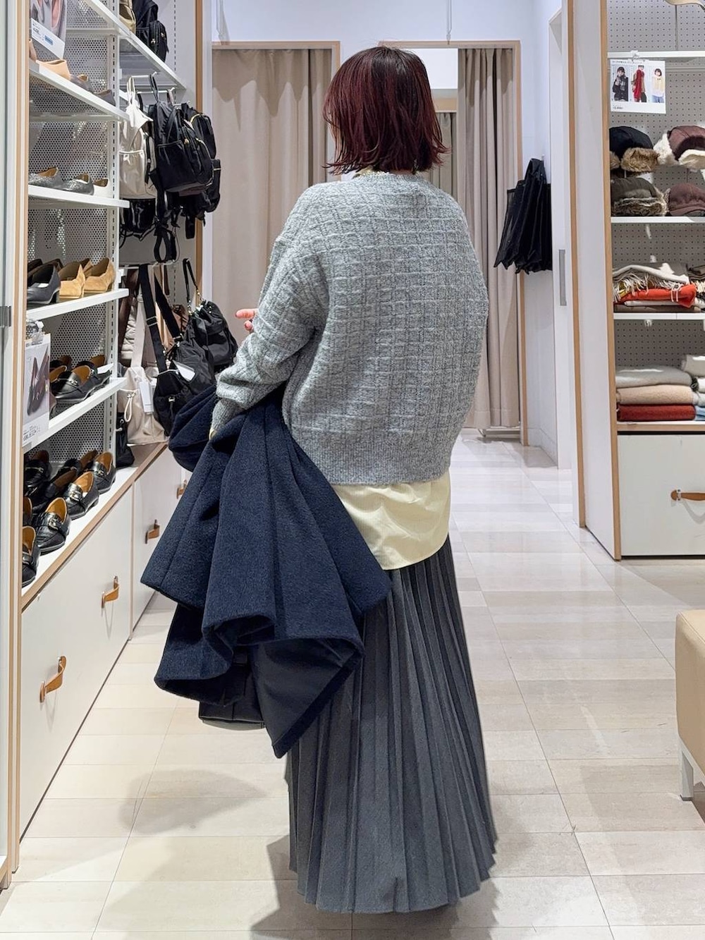 ブラック系のボストンバッグ、ブルー系のチェスターコート、イエロー系のシャツ/ブラウスを着用したレディースの冬コーディネートの7枚目の写真