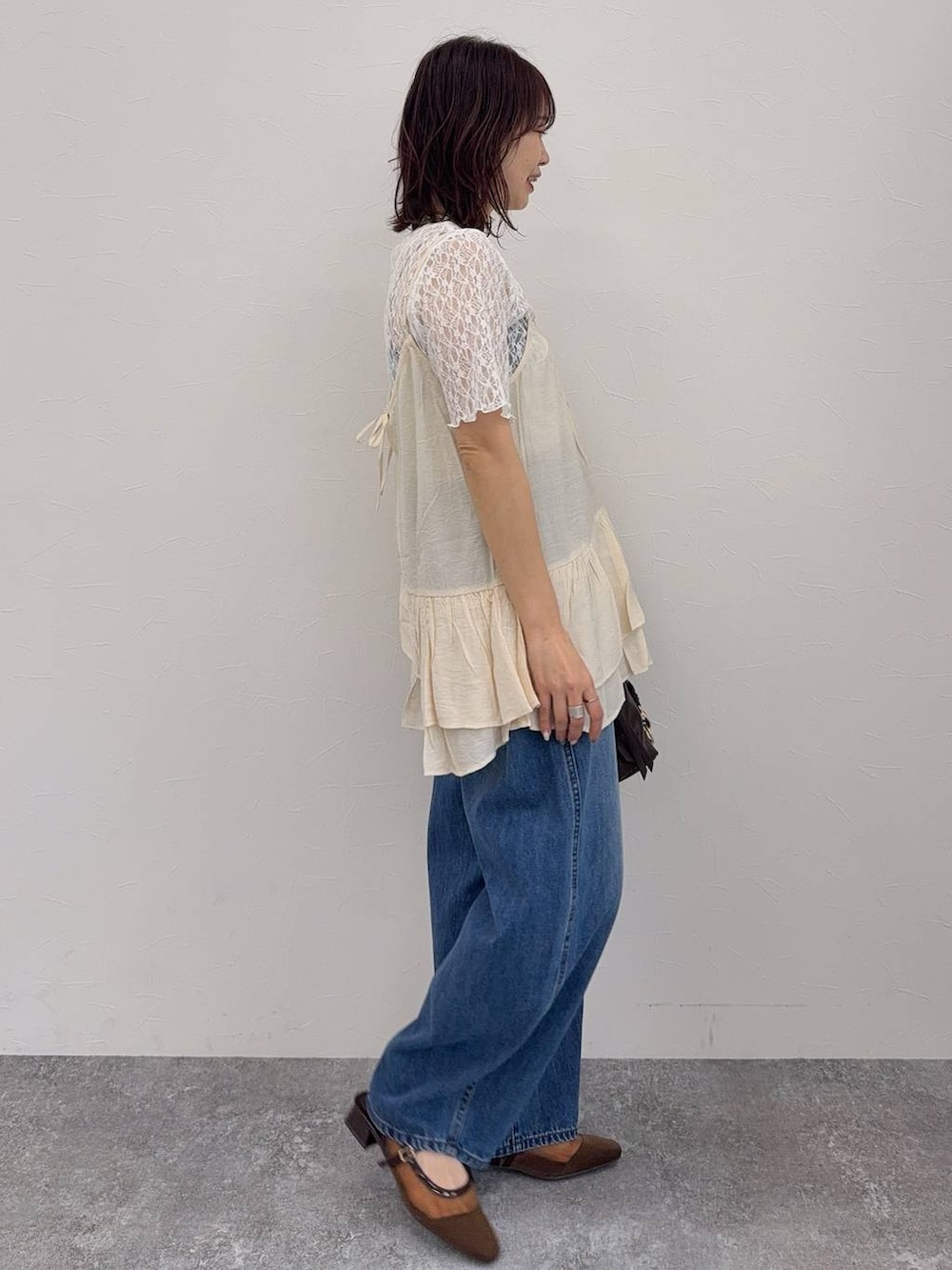 ブルー系のデニムパンツ、ブラウン系のキャミソール、ブラウン系のボストンバッグを着用したレディースの春コーディネートの6枚目の写真