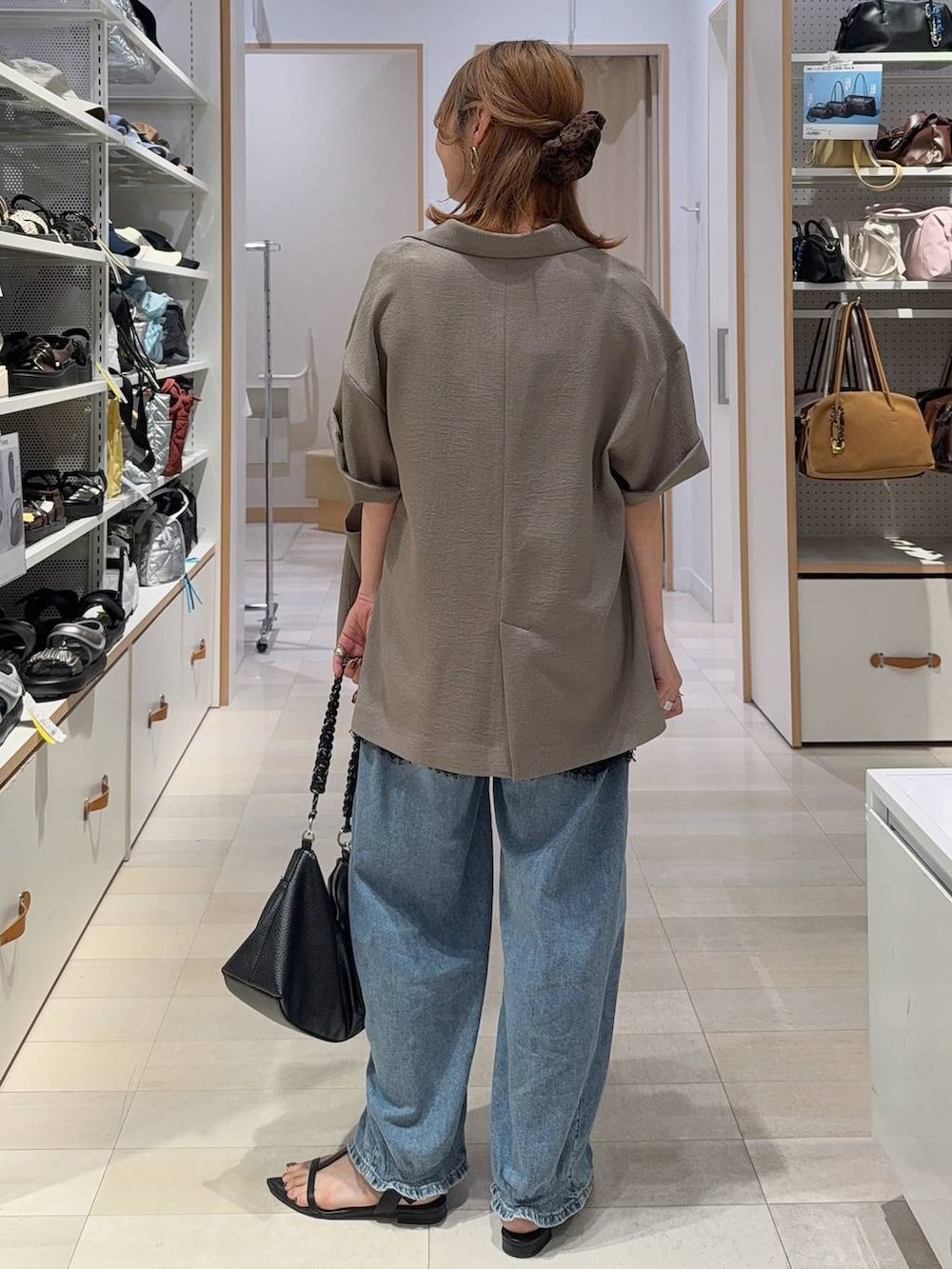 ブルー系のデニムパンツ、ブラウン系のテーラードジャケット、ブラック系のキャミソールを着用したレディースの夏コーディネートの7枚目の写真