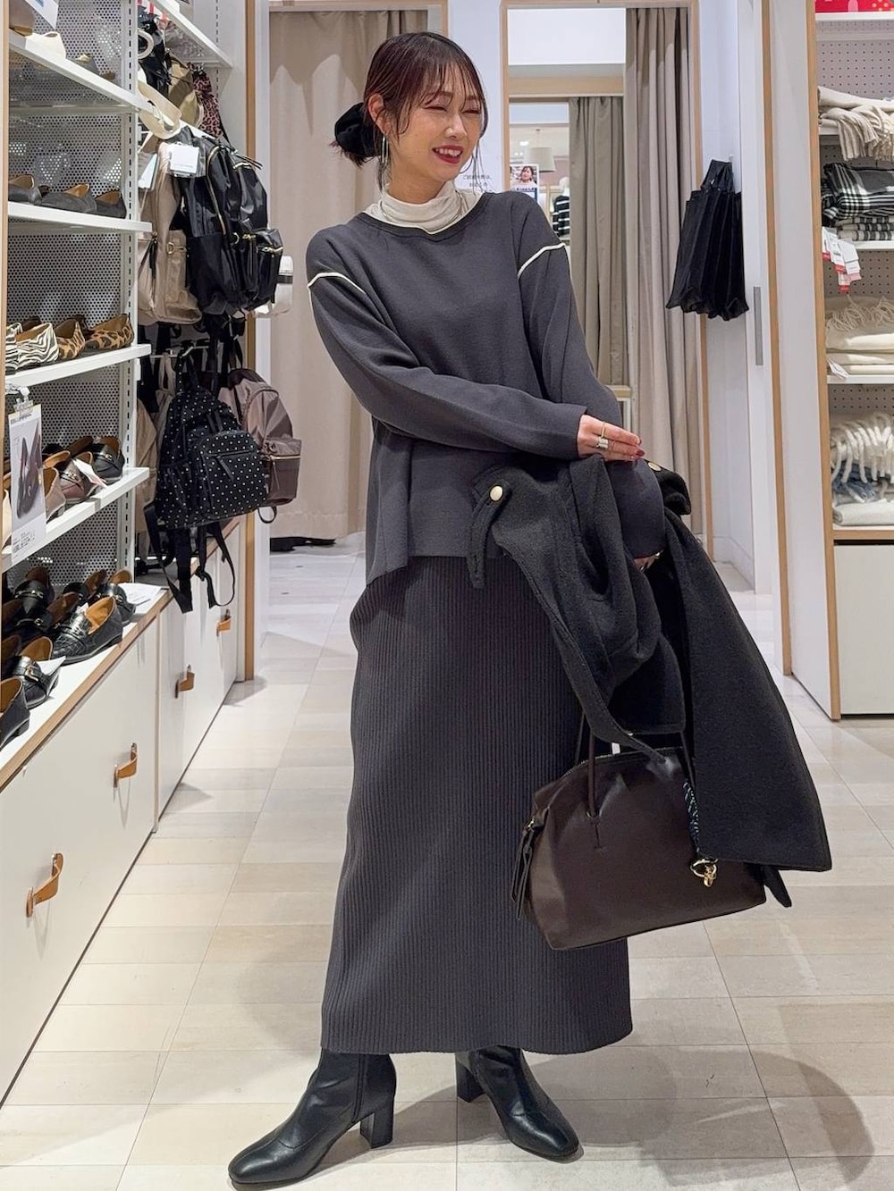 ブラウン系のボストンバッグ、ブラック系のチェスターコート、グレー系のその他パンツを着用したレディースの冬コーディネートの3枚目の写真