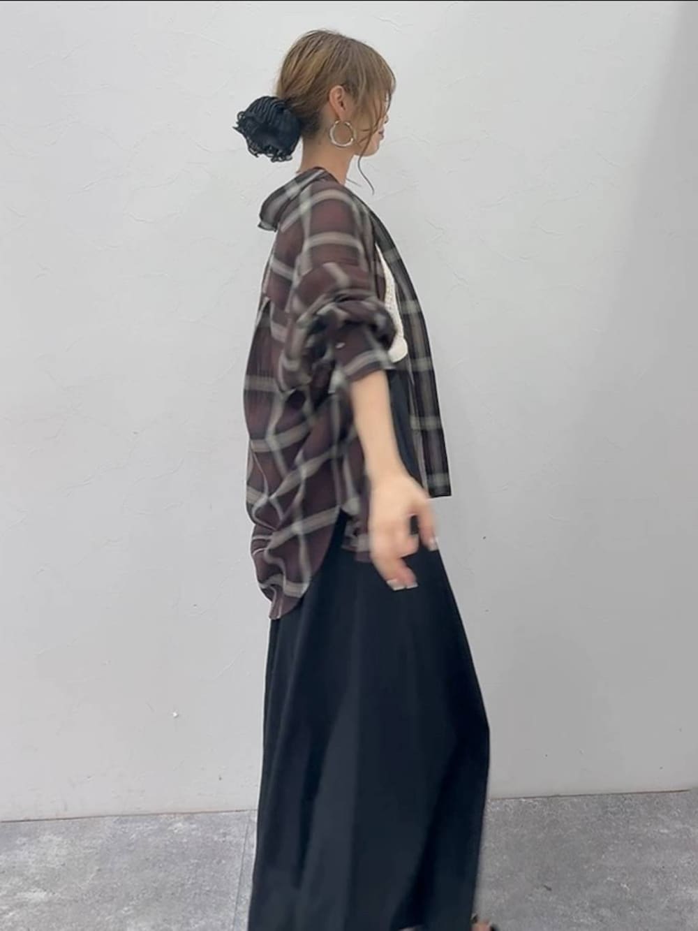 グレー系のスカート、ホワイト系のベスト、ブラック系のサンダルを着用したレディースの夏コーディネートの3枚目の写真