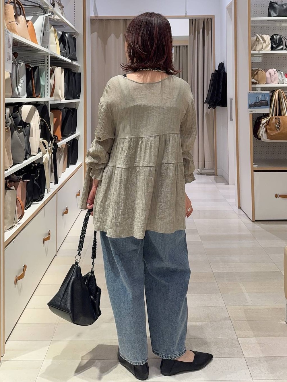 ブラック系のパンプス、ブルー系のデニムパンツ、ホワイト系のスウェットを着用したレディースの春コーディネートの10枚目の写真