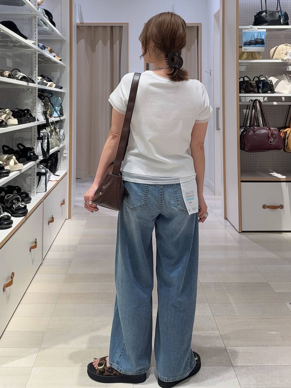 レッド系のボストンバッグ、ブルー系のデニムパンツ、ブラウン系のベストを着用したレディースの夏コーディネートの9枚目の写真