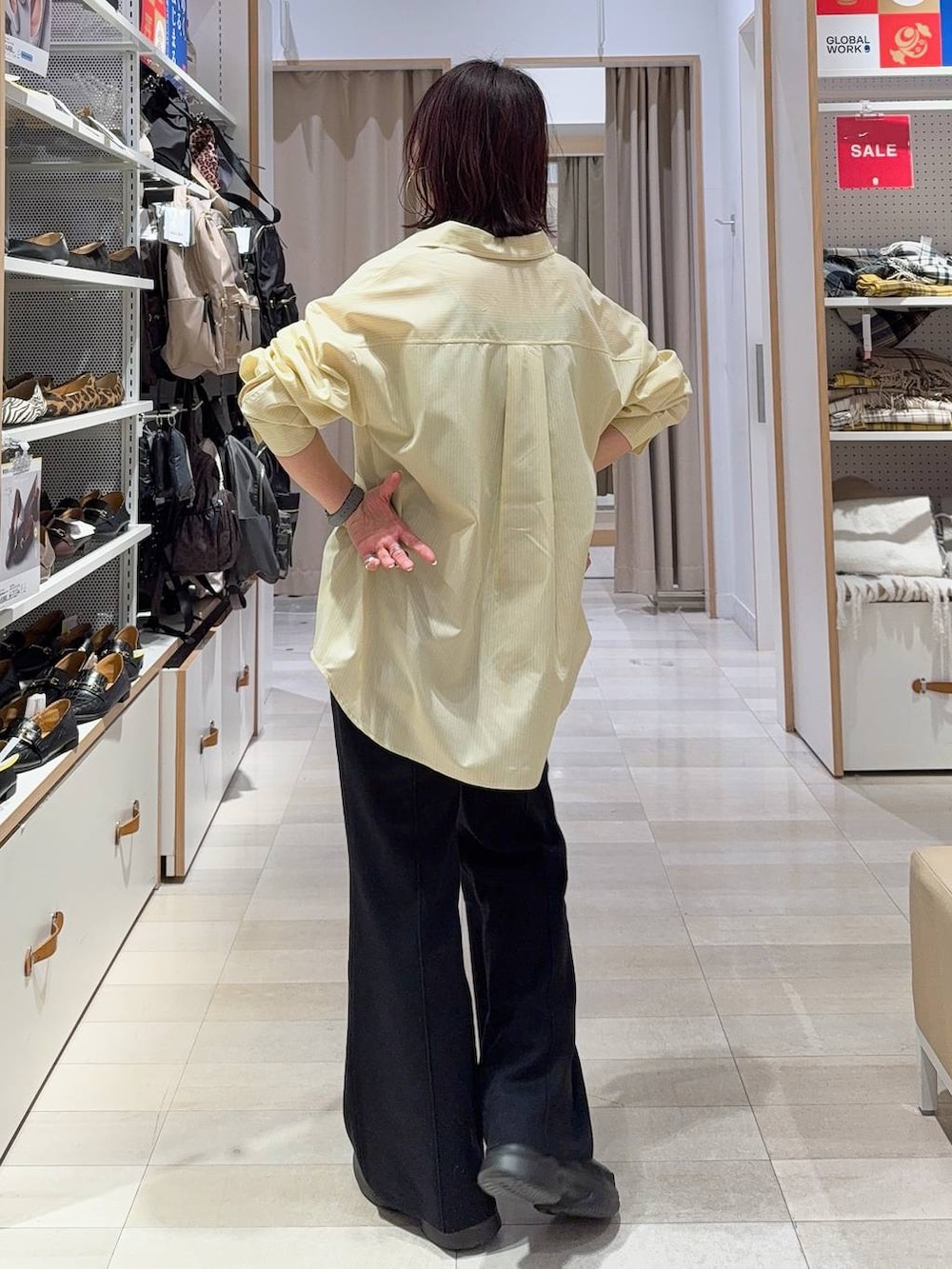 グレー系のニット/セーター、イエロー系のシャツ/ブラウス、ベージュ系のトートバッグを着用したレディースの冬コーディネートの6枚目の写真