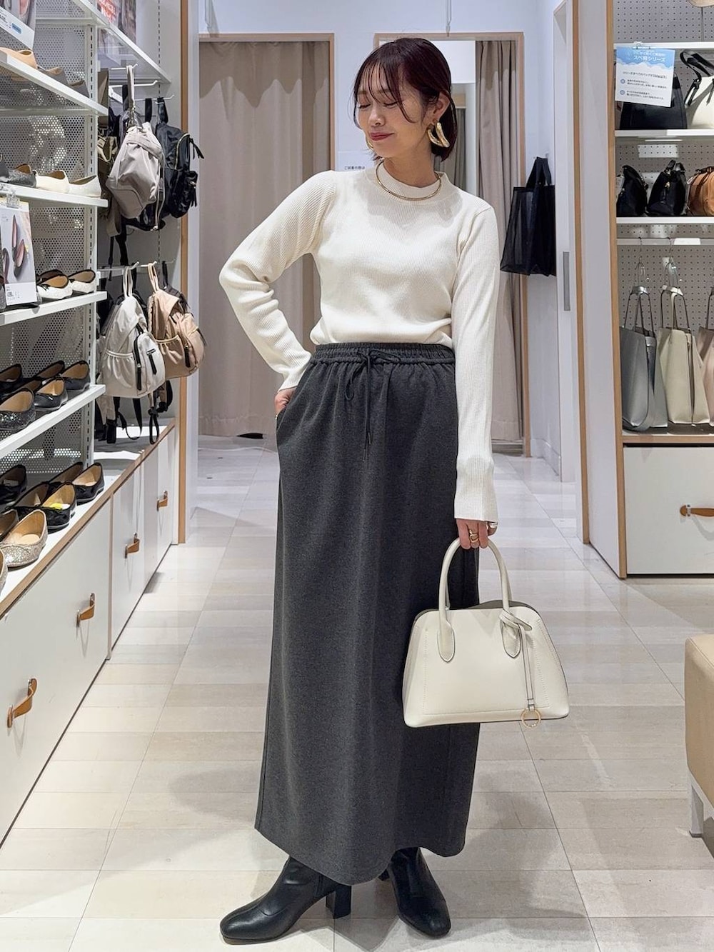 ホワイト系のショルダーバッグ、ブラック系のブーツ、ブラウン系のバレッタ/ヘアクリップを着用したレディースの秋コーディネートの3枚目の写真