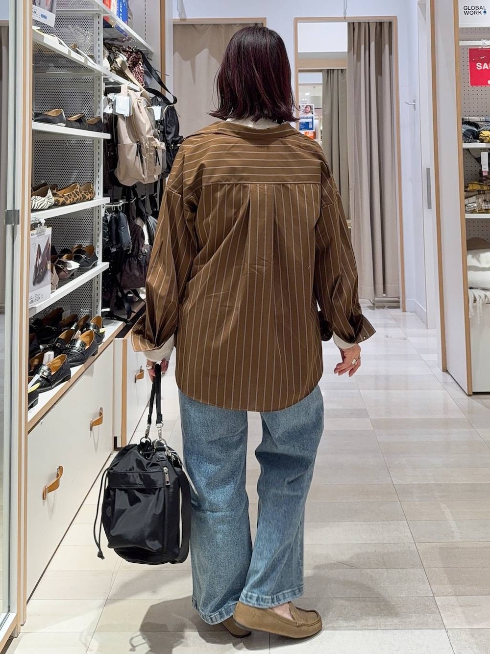 ブラック系のショルダーバッグ、ブルー系のデニムパンツ、ホワイト系のニット/セーターを着用したレディースの春コーディネートの3枚目の写真