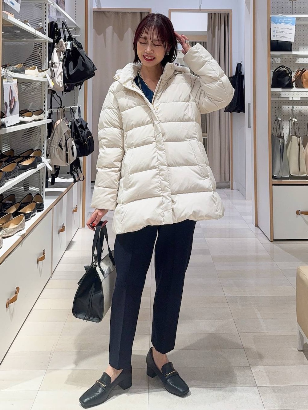 ブラック系のローファー、ホワイト系のショルダーバッグ、ベージュ系のダウンジャケット/コートを着用したレディースの秋コーディネートの2枚目の写真
