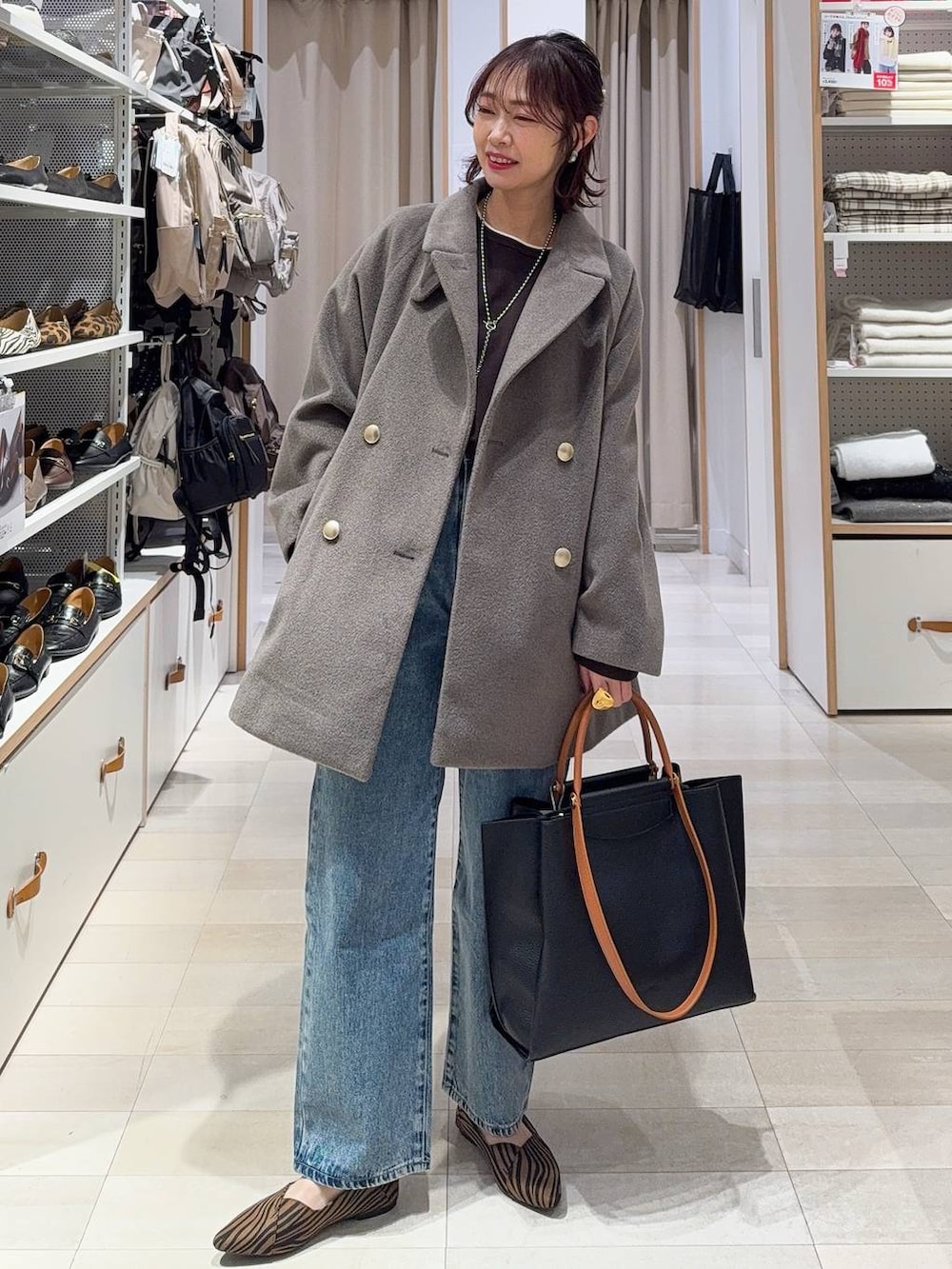 ブラウン系のショルダーバッグ、ブラウン系のチェスターコート、グレー系のワンピースを着用したレディースの冬コーディネートの4枚目の写真