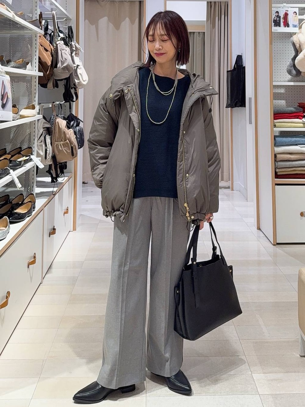 ブラウン系のダウンジャケット/コート、グレー系のスカート、ブラック系のハンドバッグを着用したレディースの冬コーディネートの5枚目の写真