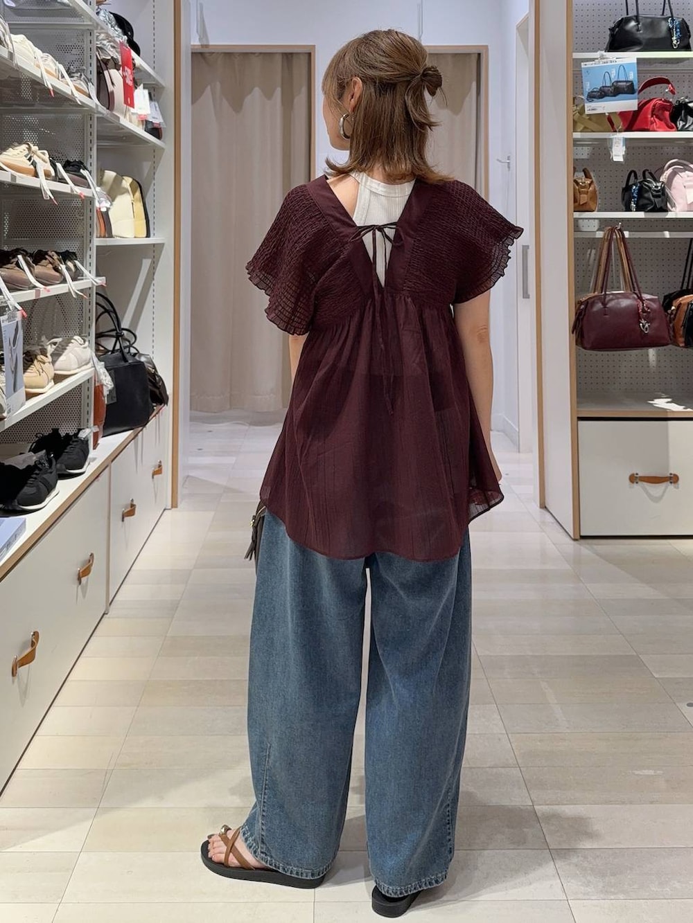 ブルー系のデニムパンツ、ブラウン系のボストンバッグ、レッド系のシャツ/ブラウスを着用したレディースの夏コーディネートの7枚目の写真