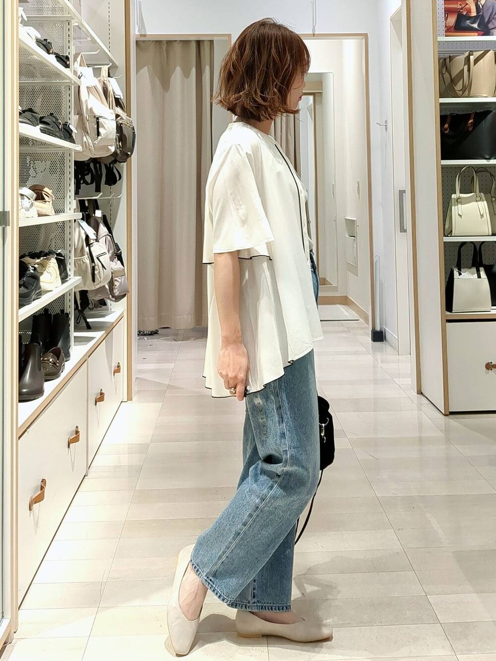 ベージュ系のパンプス、ブルー系のデニムパンツ、ブラック系のトートバッグを着用したレディースの春コーディネートの3枚目の写真