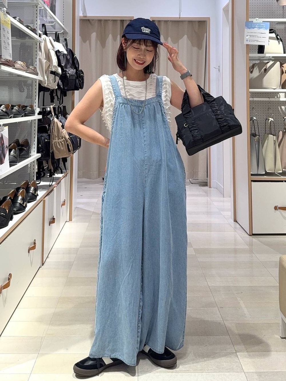 ブラック系のスニーカー、ブラック系のショルダーバッグ、ホワイト系のTシャツ/カットソーを着用したレディースの秋コーディネートの2枚目の写真