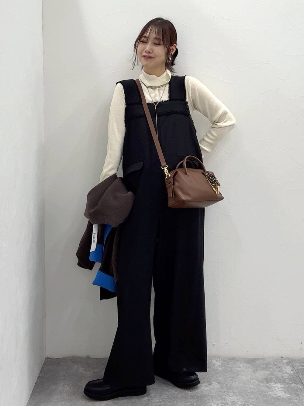 ブラック系のローファー、ブラック系のサロペット/オーバーオール、ホワイト系のニット/セーターを着用したレディースの冬コーディネートの2枚目の写真