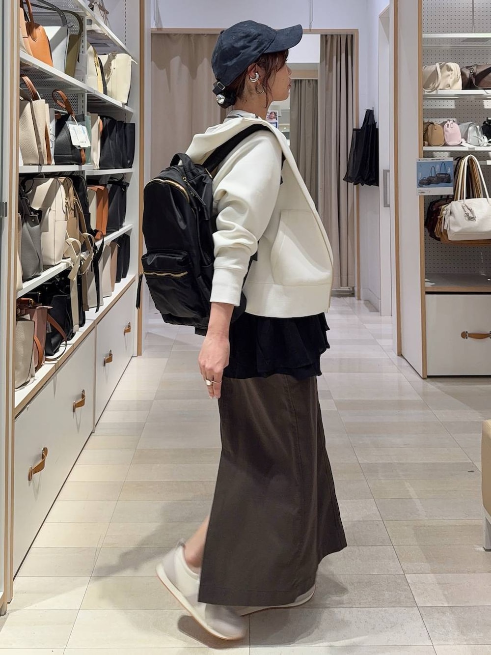 グレー系のスニーカー、ブラック系のバックパック/リュック、ホワイト系のパーカーを着用したレディースの春コーディネートの4枚目の写真