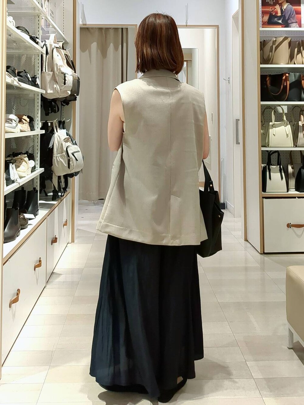 ブルー系のその他パンツ、ベージュ系のベスト、ブラック系のショルダーバッグを着用したレディースの春コーディネートの7枚目の写真