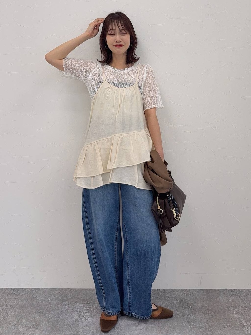 ブルー系のデニムパンツ、ブラウン系のキャミソール、ブラウン系のボストンバッグを着用したレディースの春コーディネートの3枚目の写真