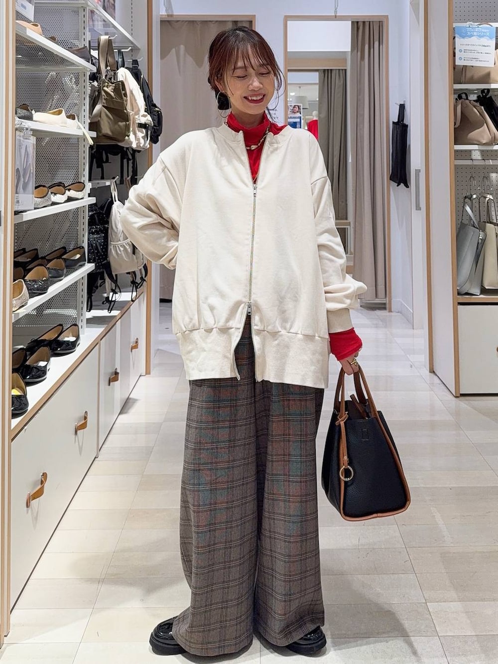 ブラック系のチェスターコート、ブラック系のショルダーバッグ、ホワイト系のTシャツ/カットソーを着用したレディースの秋コーディネートの3枚目の写真