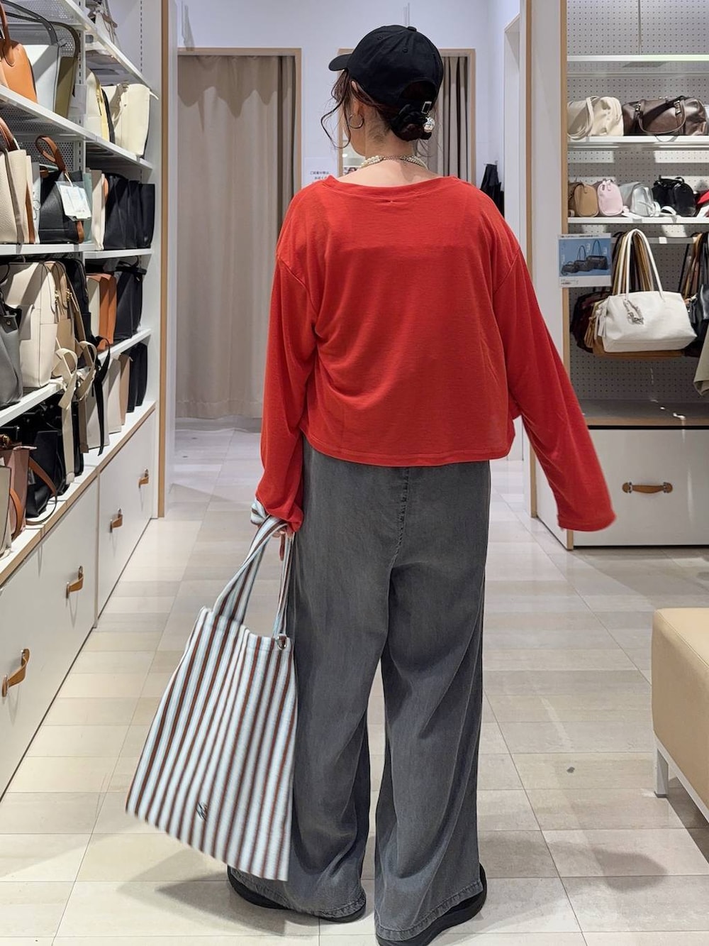 ブルー系のトートバッグ、オレンジ系のカーディガン/ボレロ、ブラック系のスニーカーを着用したレディースの春コーディネートの7枚目の写真