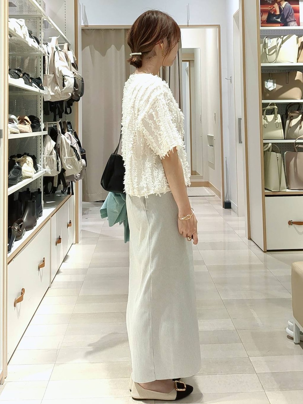 ブラック系のショルダーバッグ、グリーン系のカーディガン/ボレロ、グレー系のスカートを着用したレディースの春コーディネートの7枚目の写真