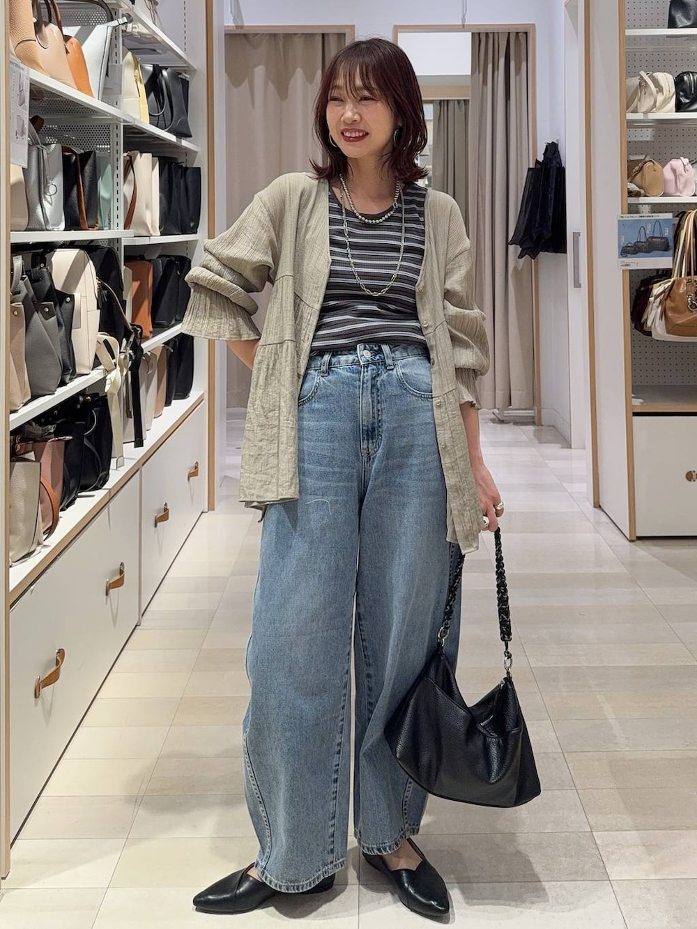 ブラック系のパンプス、ブルー系のデニムパンツ、ホワイト系のスウェットを着用したレディースの春コーディネートの4枚目の写真