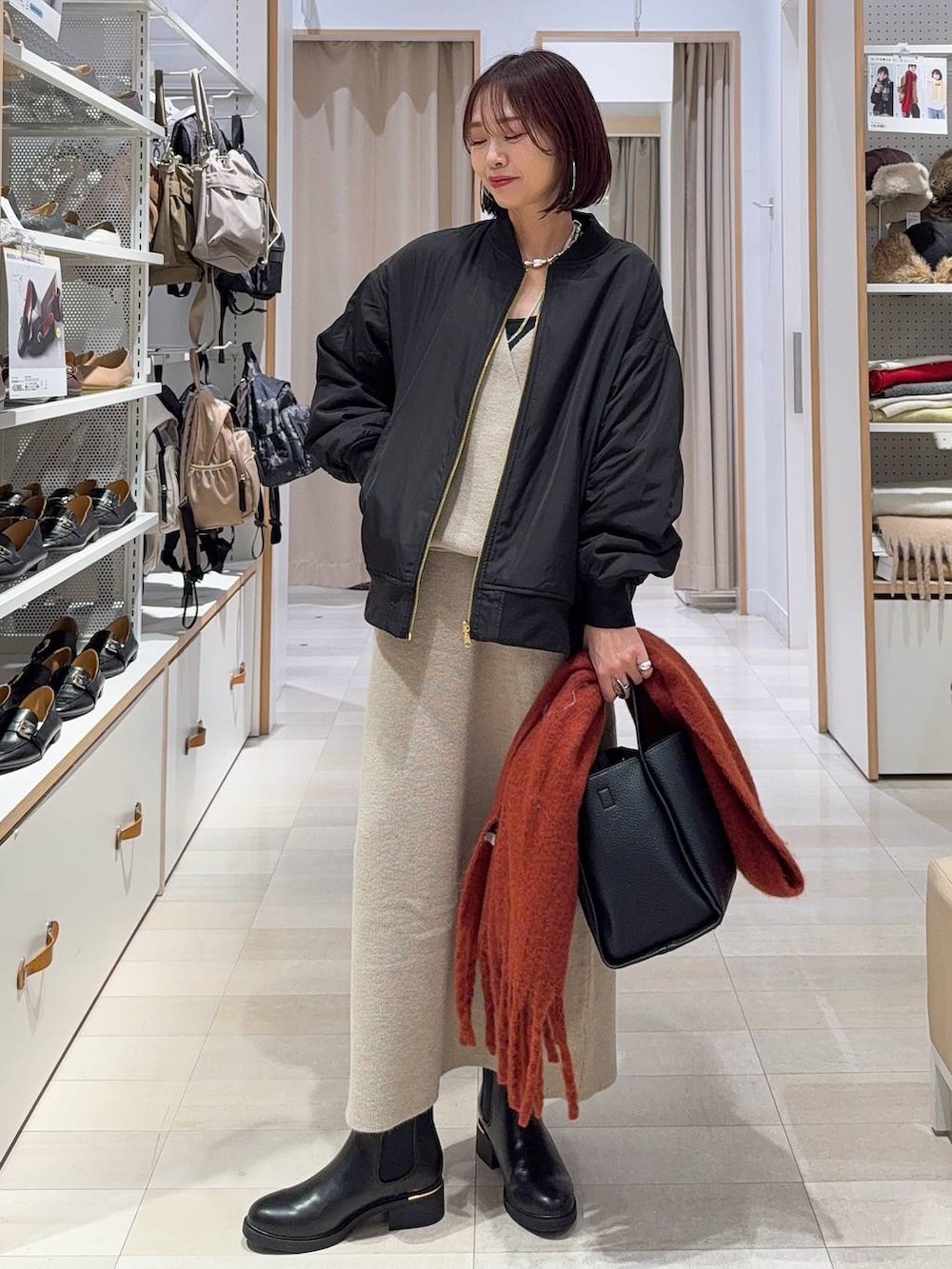 ブラック系のブルゾン、ブラウン系のスカート、ブラウン系のブーツを着用したレディースの冬コーディネートの3枚目の写真