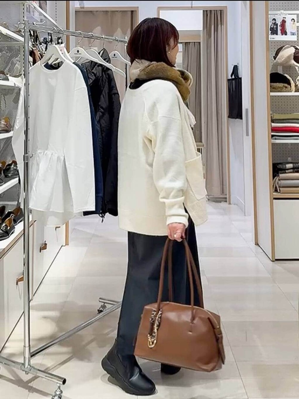 ブラウン系のボストンバッグ、ホワイト系のカーディガン/ボレロ、グレー系のスカートを着用したレディースの秋コーディネートの5枚目の写真