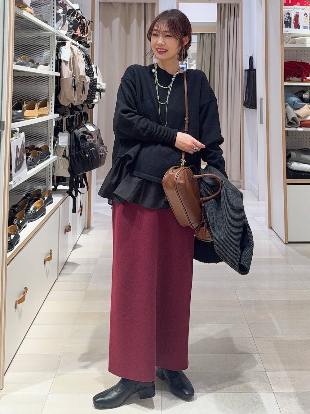 ブラック系のニット/セーター、レッド系のスカート、ブラック系のTシャツ/カットソーを着用したレディースの冬コーディネートの2枚目の写真