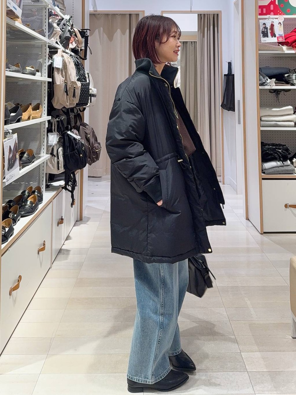 ブラック系のダウンジャケット/コート、ブラック系のボストンバッグ、ブルー系のデニムパンツを着用したレディースの冬コーディネートの5枚目の写真