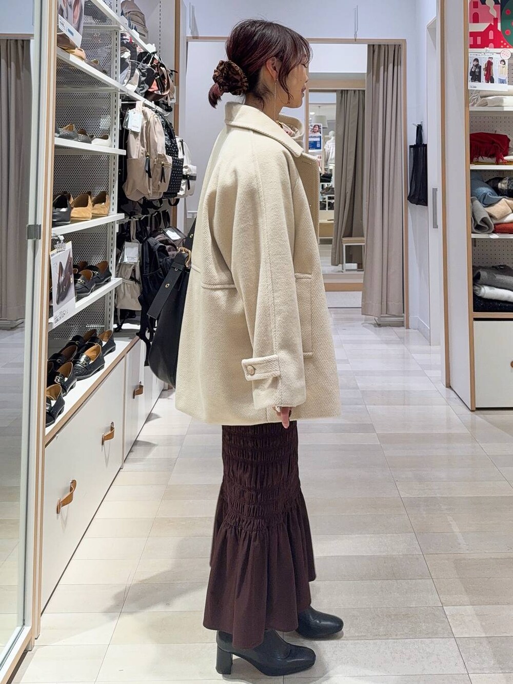 ブラック系のショルダーバッグ、ホワイト系のTシャツ/カットソー、ブラック系のブーツを着用したレディースの冬コーディネートの6枚目の写真