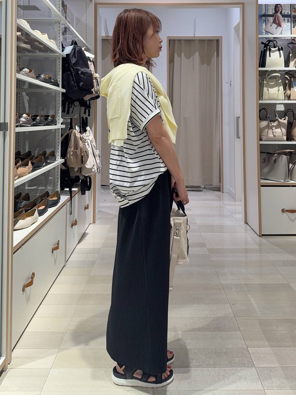 ブラック系のスカート、イエロー系のカーディガン/ボレロ、ホワイト系のトートバッグを着用したレディースの夏コーディネートの4枚目の写真