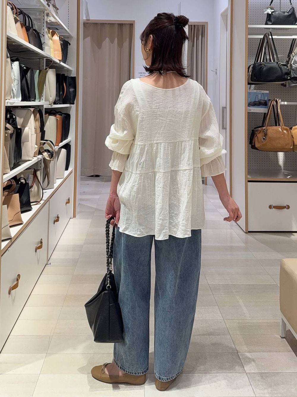 ブラック系のTシャツ/カットソー、ブラック系のスラックス、ブルー系のデニムパンツを着用したレディースの春コーディネートの9枚目の写真