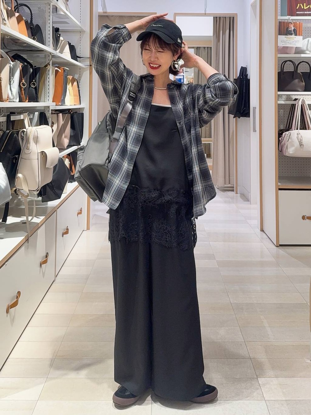 ブラック系のパンプス、ブラック系のハンドバッグ、ブルー系のデニムパンツを着用したレディースの春コーディネートの4枚目の写真